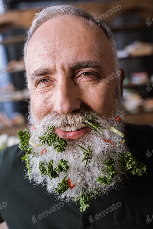Preview: Close-up portrait of smiling senior man with greens in beard