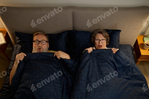 Preview: Overhead view of screaming scared old couple in bed