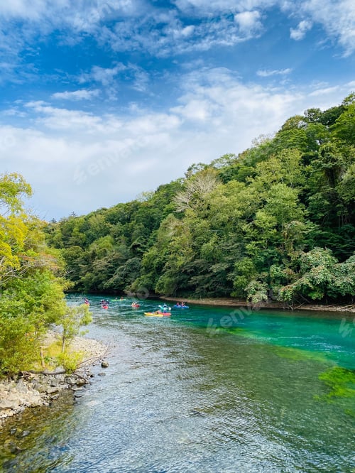 Preview: Scenic river with kayakers and lush forest.