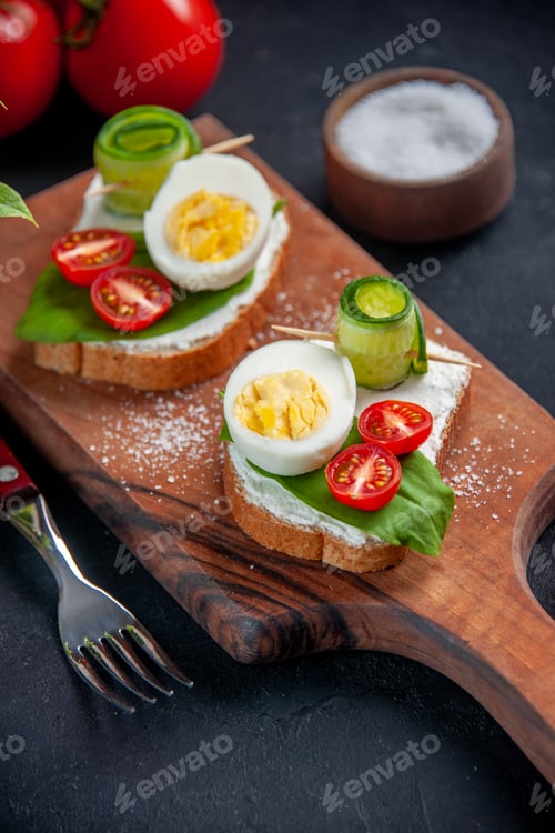 Preview: front view delicious sandwiches with tomatoes cucumbers and eggs on cutting board dark background