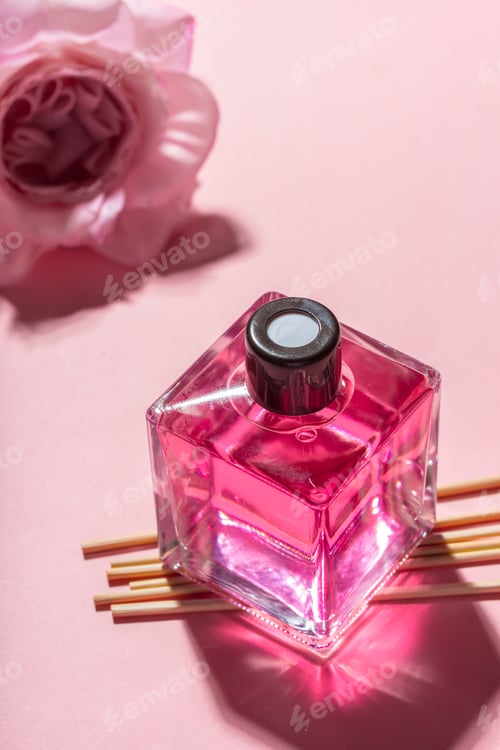 Preview: Bright pink perfume bottle on soft pink surface with flower accent