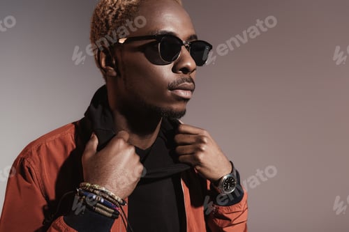Preview: Stylish young african american man straightens his jacket isolated on light background