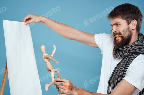 Preview: Male artist with a wooden dummy in hands drawing Creative hobby blue background
