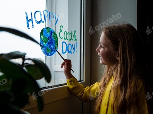 Preview: Cute little girl painting planet on window at home. Happy Earth Day April 22 greeting message.