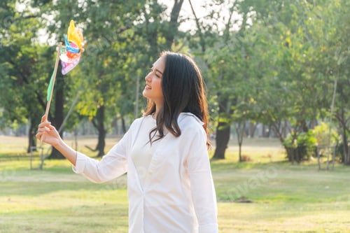 Preview: Happy Asian healthy woman playing a turbine in the park