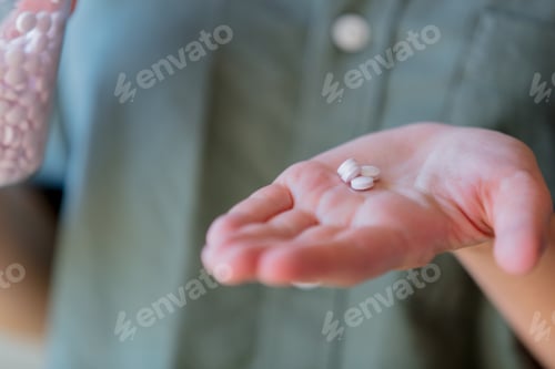 Preview: woman holding a white pills in a hand