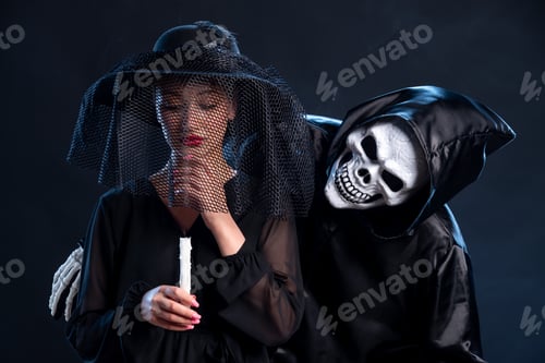 Preview: young female dressed in black and holding candle on dark desk death grim reaper funeral