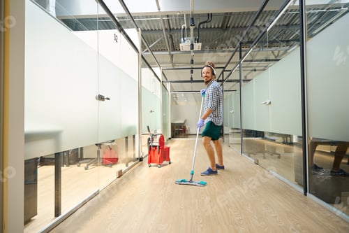 Preview: Cheerful informal mopping the floor in the office hallway