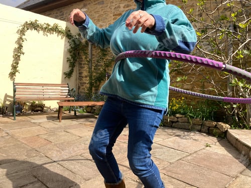 Preview: Fitness. Woman using a hula hoop as part of her exercise routine to keep fit