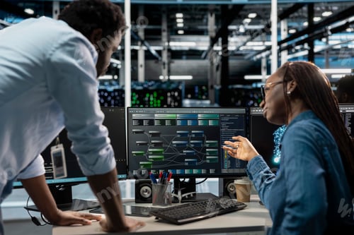 Preview: Manager supervising technician programming in server farm