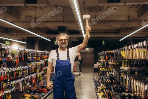 Preview: Smiling worker holding mallet in hardware store aisle