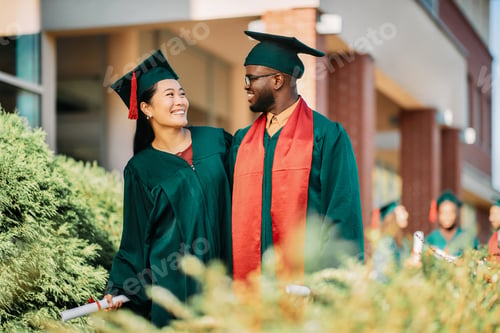 Preview: Happy multiracial college students talking on their graduation day.