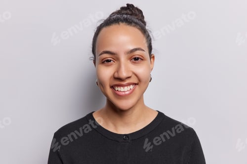 Preview: Portrait of pretty Latin woman with clean healthy skin toothy smile looks at camera feels satisfied