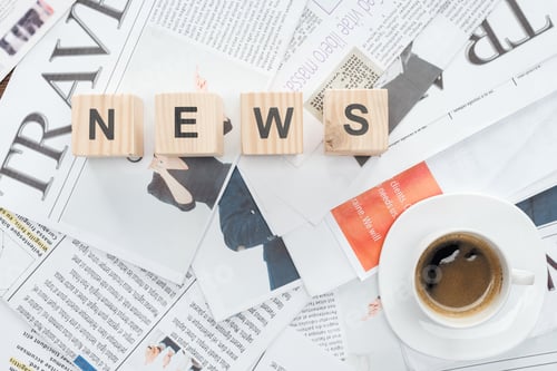 Preview: top view of wooden cubes with word news and cup of coffee on newspapers
