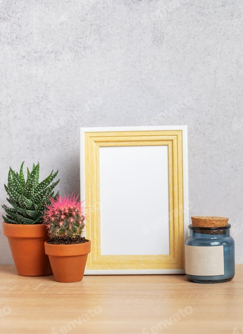Preview: Empty photo frame with cacti, candle and copy space on wooden table
