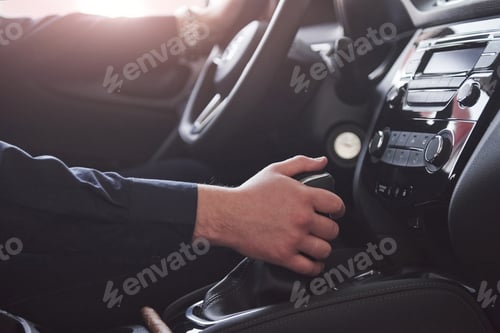 Preview: Switches gear. Close up side view of man sitting in the modern car with black interior
