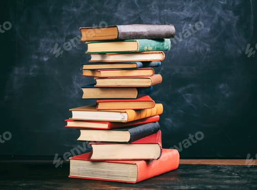 Preview: Vintage books stack on blackboard background