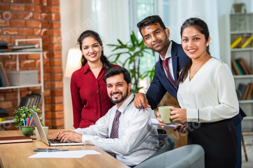 Preview: Indian young businesspeople using laptop in group meeting at desk