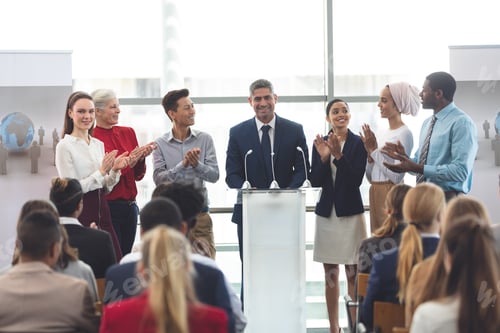 Preview: Diverse business professionals standing on podium while speaking at a business seminar in office