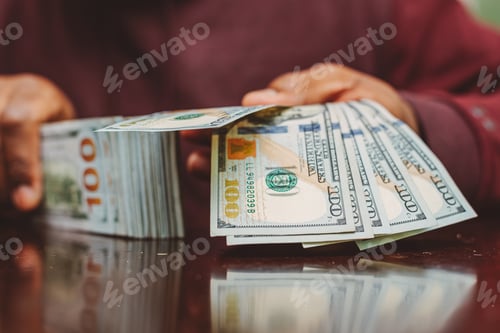 Preview: Man holding a stack of money, US one hundred dollar bills against clean white background