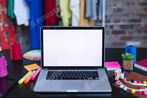 Preview: Laptop with copy space on screen lying on desk full of designers accessories