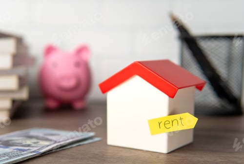 Preview: A small toy house with a yellow sticky note labeled "rent" attached to it.