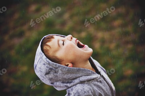 Preview: Young boy in the rain opening mouth hoping for rain drops in come into mouth!