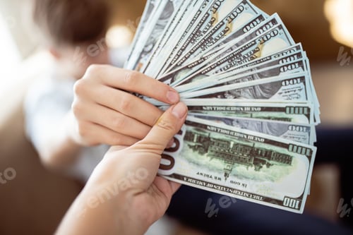Preview: Banknotes of one hundred dollars are fan-folded close-up. Hand giving money