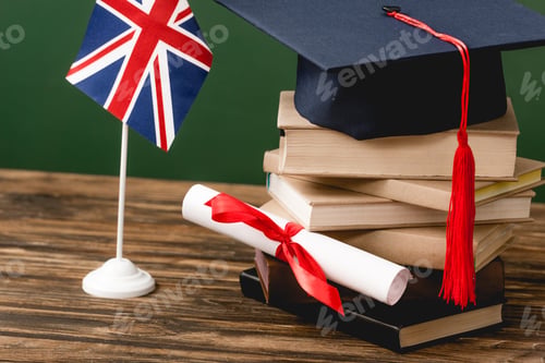 Preview: Books, academic cap, diploma and british flag on wooden surface isolated on green