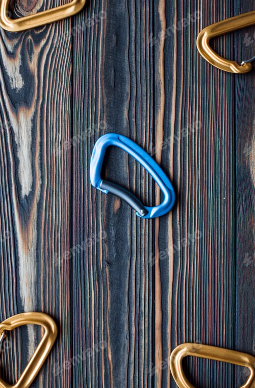 Preview: Vertical photo. Isolated photo of climbing equipment. Parts of carabiners lying on the wooden table