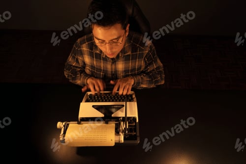 Preview: Young Man Reflecting on Poetry Day Using a Vintage Typewriter at Desk