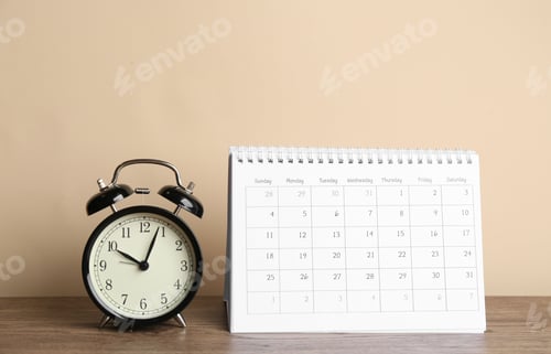 Preview: Calendar and alarm clock on wooden table against beige background