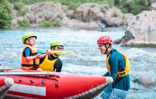 Preview: Family of three playing with water pistols near inflatable rowing catamaran