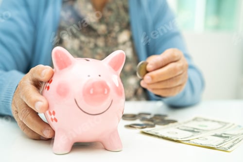 Preview: Asian elderly woman putting coin into pink piggy bank for saving money and insurance, poverty,