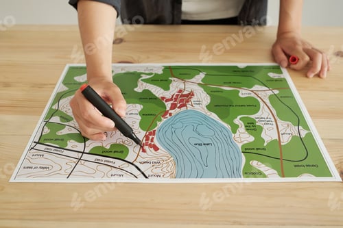 Preview: Hands of young female architect with highlighter over map of new district