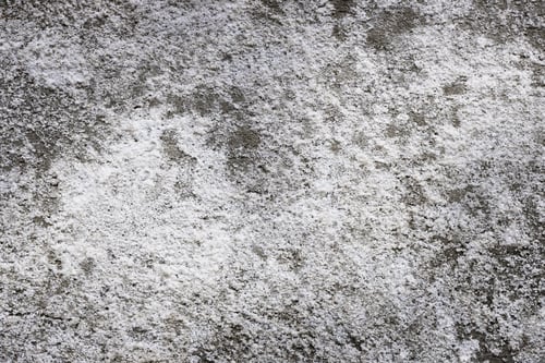 Preview: Coarse white salt crystals scattered on rough concrete surface background.