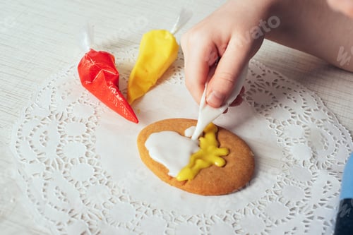 Preview: Close-up of children's hands coloring egg-shaped cookies with icing.