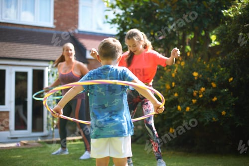 Preview: Mature woman with son and teenage daughter hula hooping in garden