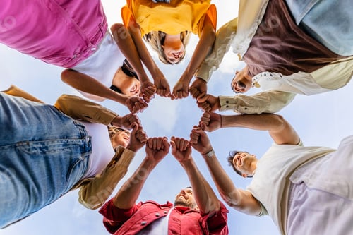Preview: Diverse group of people in circle joining hands together outdoors