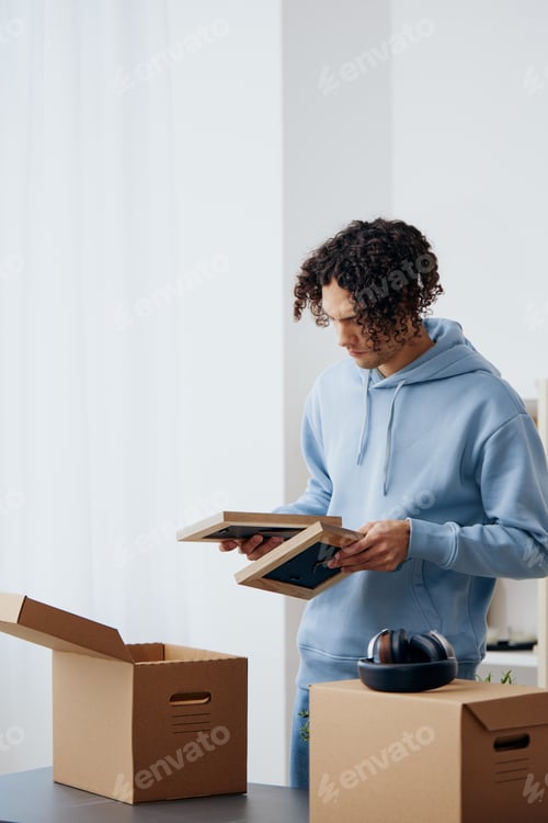 Preview: handsome guy unpacking things from boxes in the room sorting things out