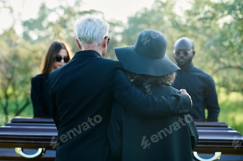 Preview: Rear view of mature grey haired man embracing his wife in black hat