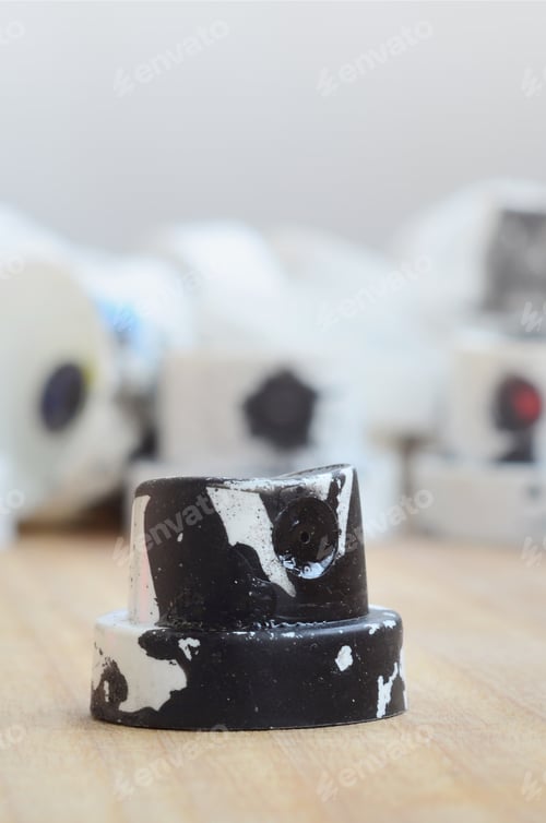 Preview: Several plastic nozzles from a paint sprayer that lie on a wooden surface against a gray wall