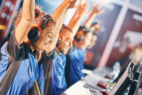 Preview: Side view of a excited mixed race girl, female cybersport gamer raising hands up, celebrating