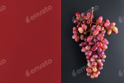 Preview: Bunch of rose grapes on a geometric double color wine red and black background, top view
