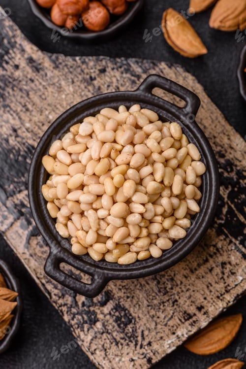 Preview: Peeled pine nuts in a bowl on a dark concrete background