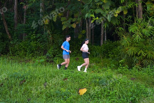 Preview: Asian Couple Jogging Together on Trail Through Lush Green Countryside
