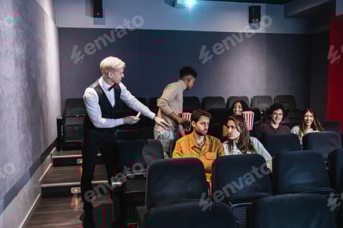 Preview: Usher checking tickets of spectators entering movie theater