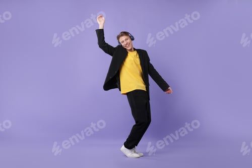 Preview: Happy man in headphones dancing on violet background
