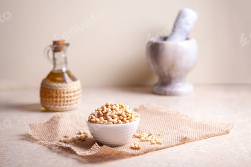 Preview: Pine nuts in a bowl on a jute napkin, cedar oil in a jug, pestle and mortar