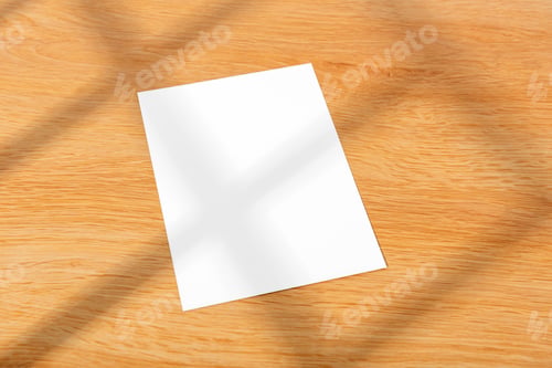 Preview: Mockup white greeting paper card on wood table background with abstract light from the window.